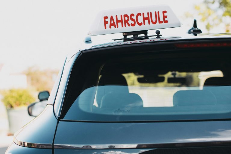 Heck eines Fahrschulautos mit beleuchtetem Fahrschul-Dachschild